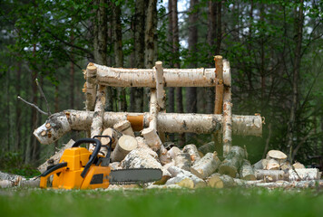 Orange chainsaw on the background of sawn logs.Harvesting firewood in the garden.Cut a tree with a chainsaw.