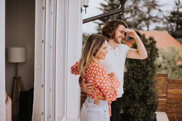 Smiling young couple in love looking in front of house brick wall