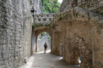Fortress wall in Kotor. Kotor is a beautiful historic city on the Unesco list. Silhouettes of walking woman under arch.