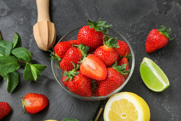 Bowl with ripe strawberry, lime, lemon and mint on dark background, closeup