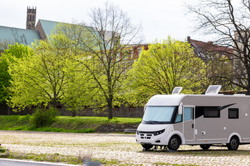Many white modern campervan recreational motor home vehicles parked in row at camper park site...