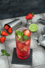 Glass of fresh strawberry mojito on tile table