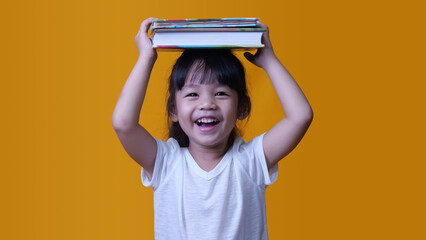 A little girl laughs with book on head. Smart child with a book. Little girl with a book on her head. A child with a book on head thinks.