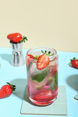 Glass of delicious strawberry mojito on color background