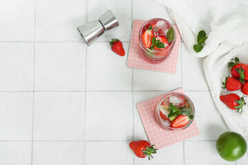 Glasses of fresh strawberry mojito on light tile background