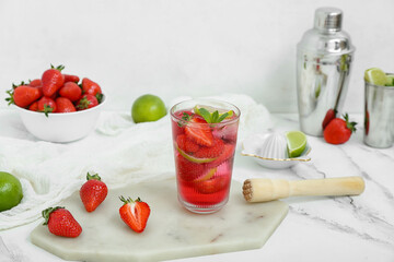 Glass of delicious strawberry mojito on light background