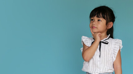 Portrait a little girl thinking and looking up, confused about an idea, would be trying to find a solution. Back to school concept. Idea and creativity concept. Copy space for your text. 