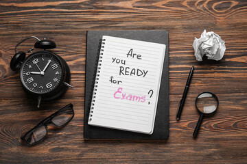 Notebooks with question ARE YOU READY FOR EXAM?, alarm clock and eyeglasses on brown wooden background