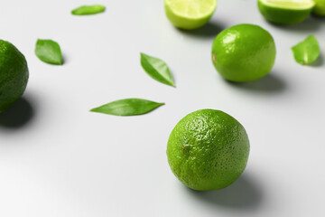 Fresh limes with leaves on grey background