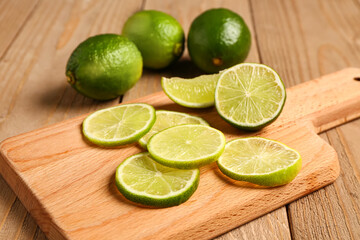 Board with slices of fresh lime on wooden background