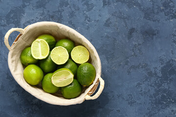 Basket with fresh limes on blue background