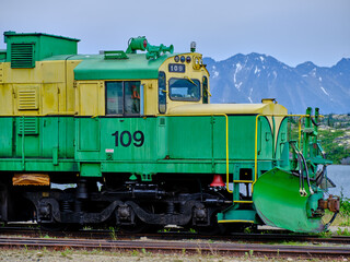 A beautiful green and yellow locomotive with a attached snow plow near Aiyansh British Columbia near the Alaskan Border