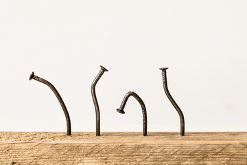 Crooked nails in a wooden board with white background. Try and fail concept.