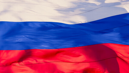 The colorful flag of Russia flutters in the wind in the rays of the evening sun. Silk texture. The...