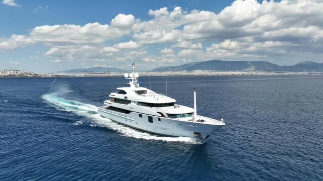 Aerial drone video of luxury yacht with wooden deck cruising open ocean deep blue Aegean sea