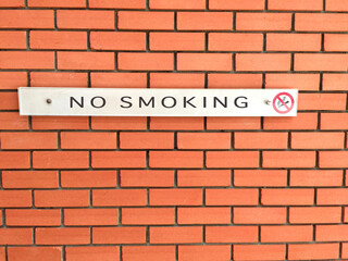 No smoking sign on an orange brick wall.