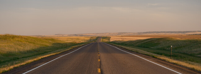 Panoramic image of a empty two-lane highway making it's way through the fertile plains and farmland of Saskatchewan Canada