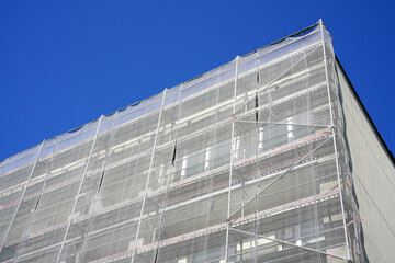 Multistorey apartment building facade renovation and thermal insulation, scaffolding with safety net
