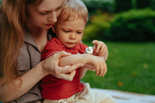 Mother puts cream on baby's hand in summer