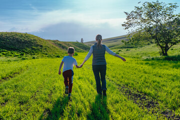 Fototapeta na wymiar Mother and son walking in the field holding hands