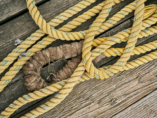 Frayed hemp rope and yellow nylon rope lay on a Gloucester Massachusetts Lobster boat dock