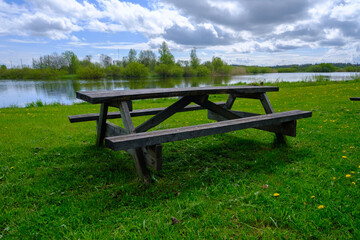 A wooden bench with a table for a picnic by the lake. Nice place to relax