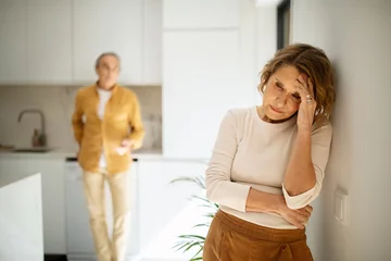 Fototapeten Upset elderly caucasian couple standing in kitchen after argue, selective focus on aged crying woman © Prostock-studio