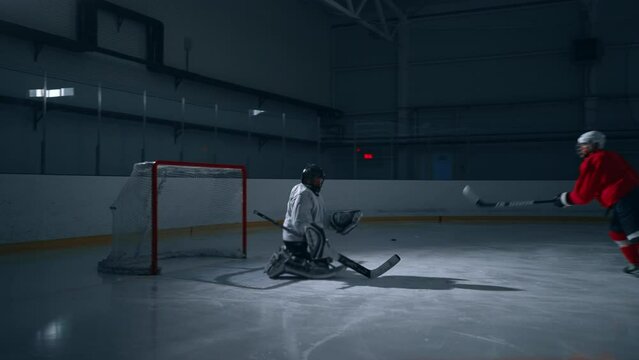 High-intensity video of a hockey player in a red jersey training on a dark ice arena, scoring a goal with ease