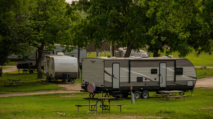 Rv trailers parked at campsite in open field with trees