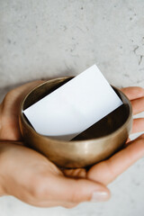 Manos sosteniendo un cuenco con una tarjeta de visita dentro