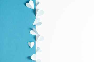 Flat lay top view of paper decoration blue hearts with shadows isolated on white and pastel blue background. Holiday paper decor with hearts on light blue table.