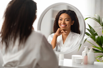 Beauty Concept. Portrait Of Attractive Black Woman Looking In Mirror At Home