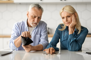 Family Financial Problems. Upset Senior Couple Counting Remaining Coins In Kitchen