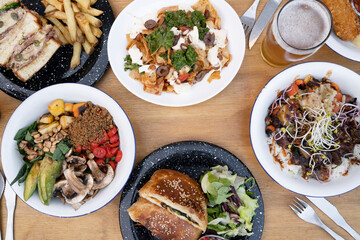 Food. Eating at the restaurant. Top view of variety of gourmet dishes, tableware and glasses of beer, on the wooden table.