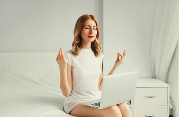 Portrait of relaxed young woman taking a break for breathing exercises working with laptop on the...