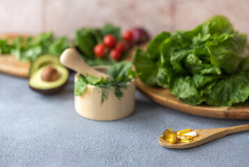 Fresh vegetables and greens and capsules with vitamins. Natural sources of vitamins versus synthetic ones. The concept of healthy lifestyle and nutrition