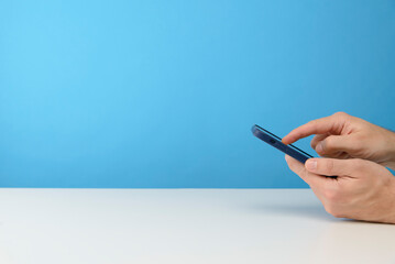 main d'un homme qui tient un smartphone sur fond bleu de studio pour publicité