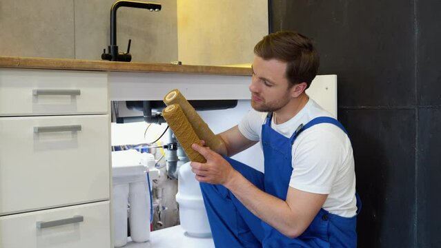 Dissatisfied plumber with two dirty aqua filters. Serviceman change water filter. Replacement aqua filter