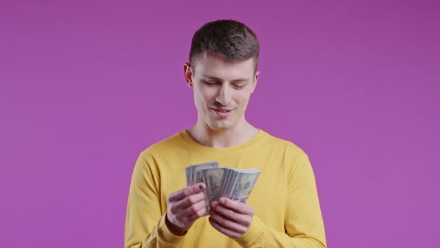 Satisfied man counting USD currency. Young millenial european guy counts money