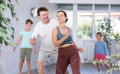 At home, fun is joy during dancing classes. Mom, dad, little son and daughter learn boogie-woogie...