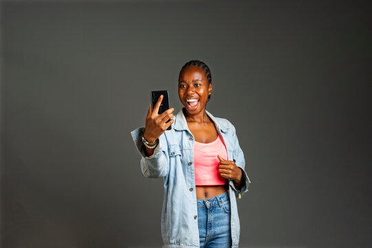 excited young black lady holding her phone