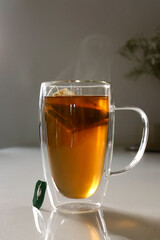 close up of a glas cup of black tea, flowers in background 