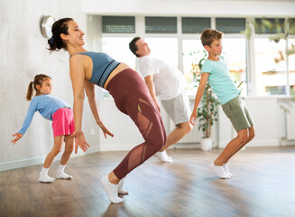 Fototapeta na wymiar Parents with daughter and son practice dance moves in fitness class