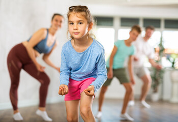 At home, child has fun during boogie-woogie class. Family teaches modern dance in background