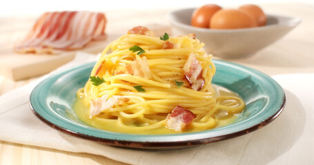 Spaghetti carbonara. Pasta with pancetta, egg, parmesan cheese. Green plate on brown background. Hard light, angle view. Traditional italian cuisine. Pasta alla carbonara. Rustic style.