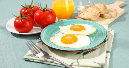 fried eggs on a plate. breakfast with fresh vegetables and bread on the table. sunny morning. country style. organic farm food