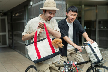 飼い犬を連れて自転車で散歩に向かう男性2人組