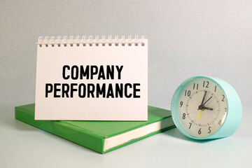 Company Performance lettering in notepad with cup of coffee and pens