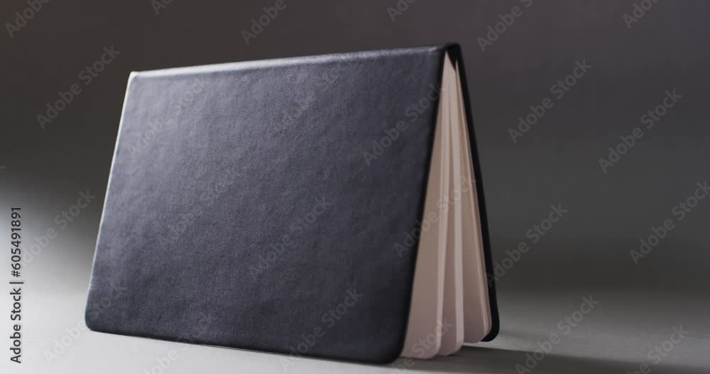 Poster close up of open black book standing horizontal with copy space on gray background in slow motion