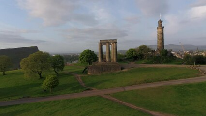 Spring morning light on Calton Hill, Edinburgh as drone circles the tower and Greek columns at sunrise revealing the city - Powered by Adobe